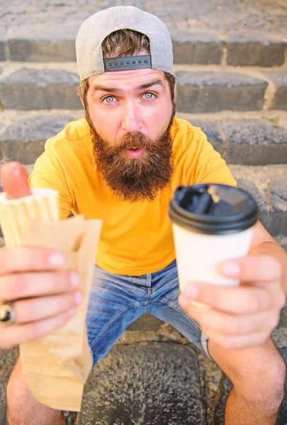 A energia da comida de rua contribui significativamente para a dieta. Homem barbudo desfrutar de almoço rápido escadas fundo. Hipster come cachorro quente. Hipster desfrutar de copo de papel de bebida de cachorro quente. Refeição de fast food para almoço — Fotografia de Stock