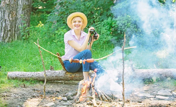 Mulher turista detém binóculos enquanto se senta em log perto de fogueira. Observando o conceito de natureza. Garota gosta de caminhar na floresta observando a natureza. Seu hobby é ornitologia. Expedição ornitologia menina na floresta — Fotografia de Stock