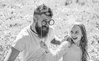 Baba ve kızı, grassplot, arka planı yeşil çimenlerin üzerinde oturur. Daddys Prenses kavramı. Aile açık havada eğlence harcamak. Çocuk ve babası crown ve gözlük ile poz booth öznitelikleri fotoğraf