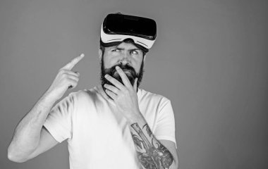 Sakal ve bıyık Vr gözlük, mavi arka plan ile olan adam. Adam Vr gözlük veya baş ile ekran monte. Gadget'ı işaret parmağı ile işaret düşünceli yüzündeki hippi. VR teknolojisi kavramı