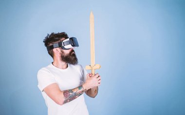 Hipster ciddi bir yüz üzerinde sanal gerçeklik oyun oyun keyfini çıkarın. Oyun kavramı. Vr gözlük, açık mavi renkli sakallı adam. Adam kafa monte ekran ile kılıç, oyun Vr oyunda mücadele tutar