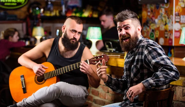 Live music concert. Acoustic performance in pub. Hipster brutal bearded with friend in pub. Man play guitar in pub. Cheerful friends sing song guitar music. Relaxation in pub. Friends relaxing in pub
