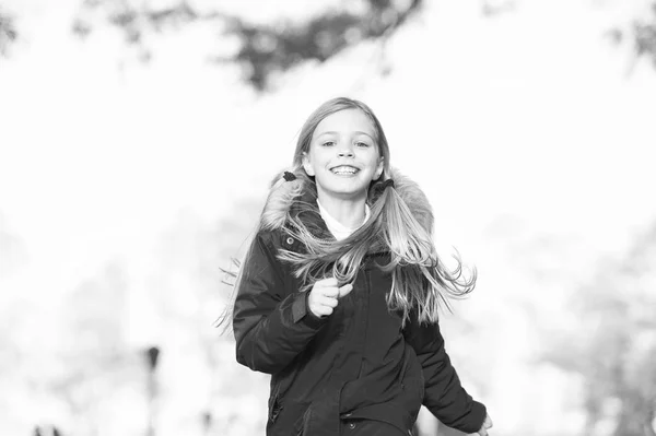 Kind in Laufbewegung im Freien. Kind blonde lange Haare laufen warme Jacke im Freien. Mädchen glücklich in rotem Mantel genießen Herbst Naturpark. Kinder tragen modische Jacke mit Kapuze. Herbstbekleidung und Modekonzept — Stockfoto