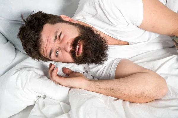 Lusta reggel. Pihenj és aludj. A szakállas fickó fehér lepedőn alszik. Egészséges alvás és jólét. Férfi szakállas hipszter álmos az ágyban. Kora reggel. Álmatlanság és alvászavarok — Stock Fotó