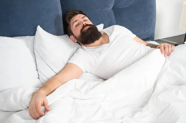 Uyku bozuklukları kavramı. Adam sakallı hippi uyku ile ilgili sorunlar yaşıyorsanız. Yatakta yatan adam rahatla ve uykuya çalışın. Gevşeme teknikleri. Uyku ve uyanıklık ihlali. Ne Uzun bir gece — Stok fotoğraf