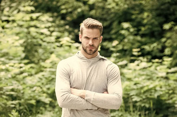 Athlète avec les bras croisés dans le parc d'été. Un homme fort prêt à s'entraîner à l'air frais. Convient et macho confiant sur extérieur ensoleillé. Activité sportive et d'entraînement. Bien-être et soins du corps — Photo