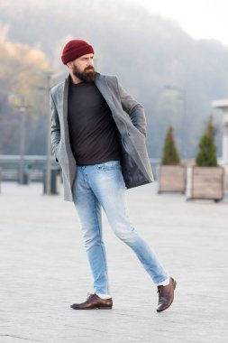 Yürüyüş yenileniyor. Hippi kıyafet ve şapka aksesuar. Şık casual kıyafet bahar mevsimi. Erkek giyim ve erkek moda kavramı. Adam hipster şık moda palto ve şapka sakallı. Rahat kıyafet