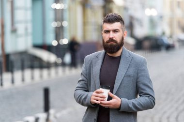 Gevşeme söz konusu. Adam hipster içki kahve kağıt bardak sakallı. İyi bakımlı işadamı kahve arası açık havada kentsel arka plan tadını çıkarın. Düşünceli ama rahat. Yürümek ve taze sıcak kahve keyfini çıkarın