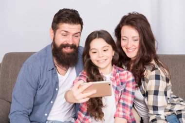 Evde mutlu bir aile. Küçük kız anne ve babasıyla smartphone kullanın. Aile mutlu ruh hali ile. Mutlu aile selfie. Sakallı erkek ve kadın kızı çocuk ile. Mutlu bir aile. Parlak anlar yakalama