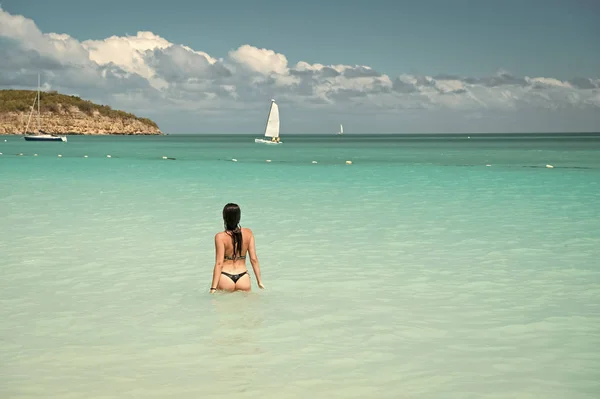 Flicka badkläder azure kristall hav vatten bakifrån. Semester lyx havsstrand resort. Simma genom magiska turkosa lagunen. Kvinna sexig kropp avkopplande havet stranden Antigua. Njut av paradiset — Stockfoto