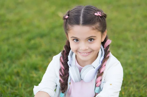 明るい面を見てください。子育ての幸せな子供に秘密。女の子のかわいい子供は緑の草の背景。屋外でリラックスした健康的な感情的な幸せな子供。幸せになる自分。女の子モダンなヘッドフォンを楽しむリラックス — ストック写真