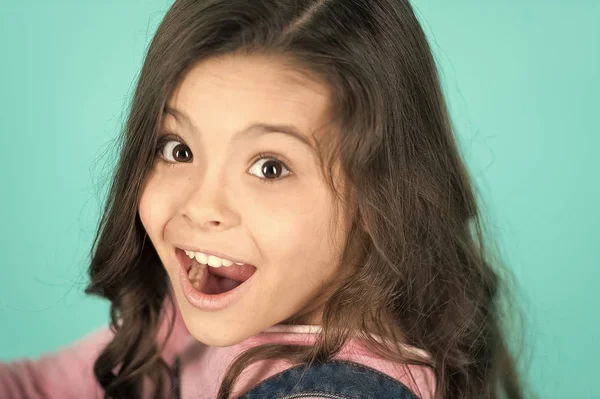 Criança surpresa com boca aberta em fundo azul. Menina feliz com cabelos longos e saudáveis morena. Beleza excepcional para o rosto excepcional. Cuidados dentários. Salão de beleza — Fotografia de Stock