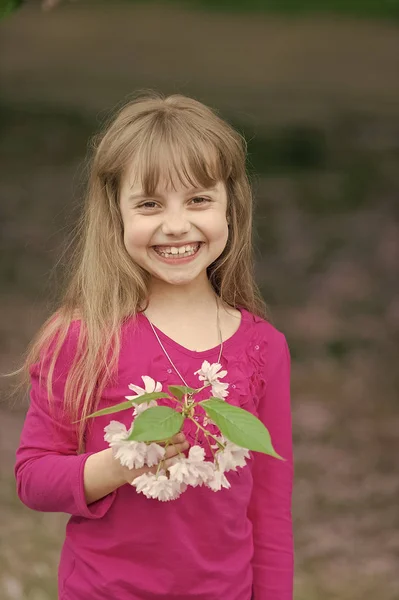 Liten flicka håller våren sakura blomma — Stockfoto