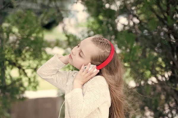 Κοριτσάκι να ακούσετε μουσική στο πάρκο καλοκαίρι. Μελωδία ήχο και mp3. Παιδί Απολαύστε μουσική στα ακουστικά εξωτερική. Παιδί της μόδας και της σύγχρονης τεχνολογίας. Καλοκαιρινές διακοπές και διασκέδαση — Φωτογραφία Αρχείου