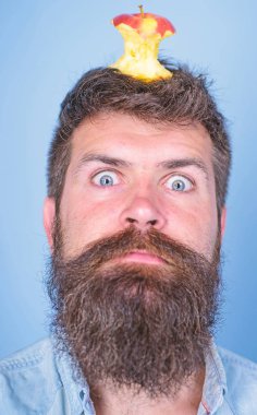 Hipster şok ile elma güdük hedef üzerinde kafa mavi arka plan, yüz kadar yakın. Kilo kaybı gol. Adam yakışıklı hipster uzun sakal neredeyse kafasına elma güdük hedef olarak yem. Canlı hedef kavramı