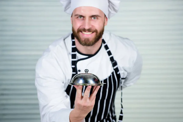 Cheerful and polite restaurant stuff. Master chef serving meal in restaurant. Chef cook in uniform standing with delicious dish. Handsome man in apron and cook hat. He is a real master cook