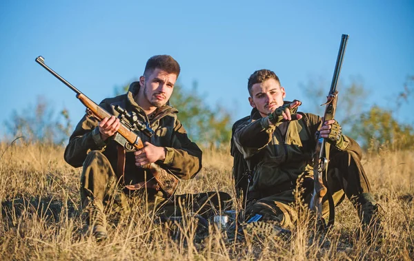 Discussing catch. Hunters with rifles relaxing in nature environment. Hunter friend enjoy leisure in field. Hunting with friends hobby leisure. Hunters gamekeepers relaxing. Rest for real men concept