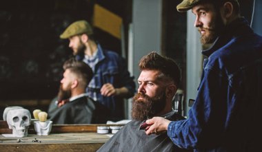 Sakallı hippi şık berber dükkanı olarak profesyonel kuaför tarafından hizmet veren cape kaplı. Damat kavramı. Sakal hipster istemcisinin, ayna yansıma arka plan üzerinde damat ile meşgul berber