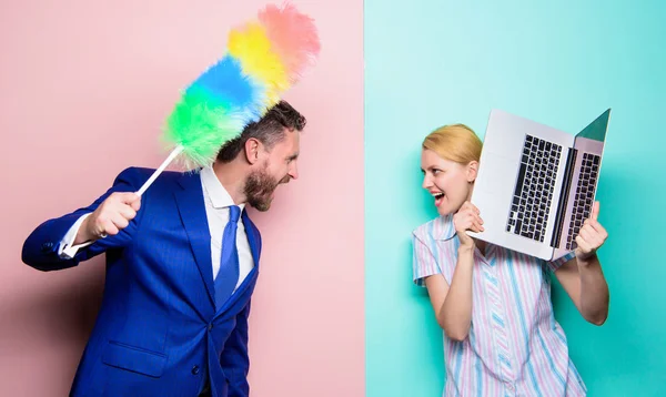 En familj gräl. Städning eller business. Affärsmannen och hemmafru. Familjen par. Man stå med damm borste medan hustru hålla laptop. Par stilig man och vacker kvinna — Stockfoto