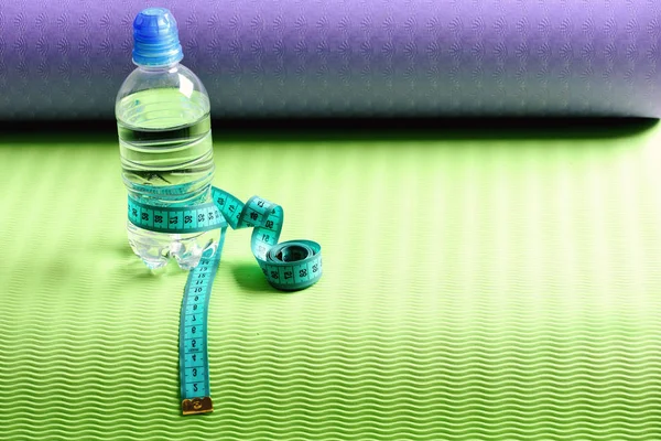 Water bottle and flexible ruler in blue on yoga mat