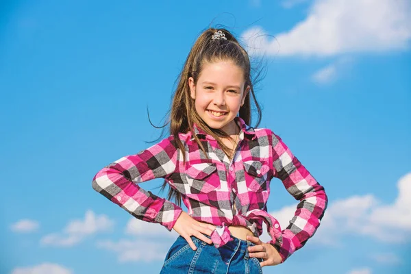 Niño linda chica pelo largo cola de caballo cabello. Chica modelo de moda. Elegante chico de moda. Concepto de moda infantil. Niña a cuadros camisa de moda posando día soleado azul cielo fondo —  Fotos de Stock