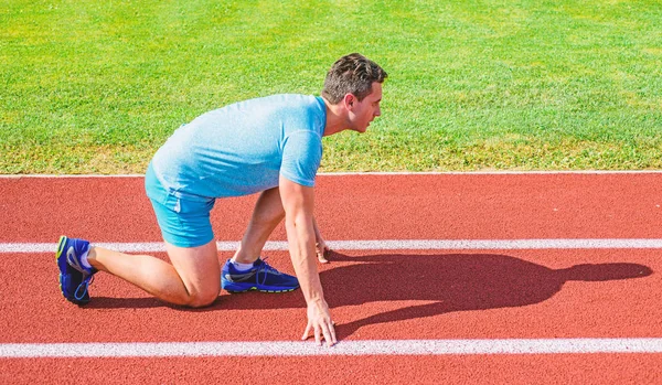 Homem atleta corredor stand baixo início posição estádio caminho ensolarado dia. Corredor pronto para ir. Esforçai-vos pela vitória. Conceito de motivação desportiva. Corredor adulto preparar corrida no estádio. Como começar a correr — Fotografia de Stock