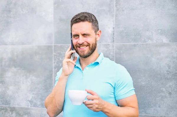 Il caffè può essere reimmaginato all'infinito fare qualcosa di nuovo vecchio come imprenditori mestiere e reinventare le imprese. Uomo bere cappuccino parlare telefono grigio muro di sfondo. Piacevole pausa caffè al lavoro — Foto Stock