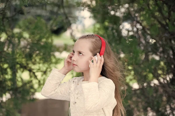 Liburan musim panas dan menyenangkan. Gadis kecil mendengarkan musik di taman musim panas. Anak-anak menikmati musik di headphone outdoor. Fashion anak dan teknologi modern. Suara melodi dan mp3 — Stok Foto