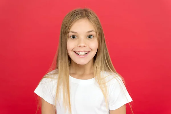 Brilliant smile concept. Girl cute smiling face over red background. Emotional kid happy smiling face. Sincere emotion. Cheerful adorable girl smiling. Positive and optimistic. Smiling beauty — Stock Photo, Image
