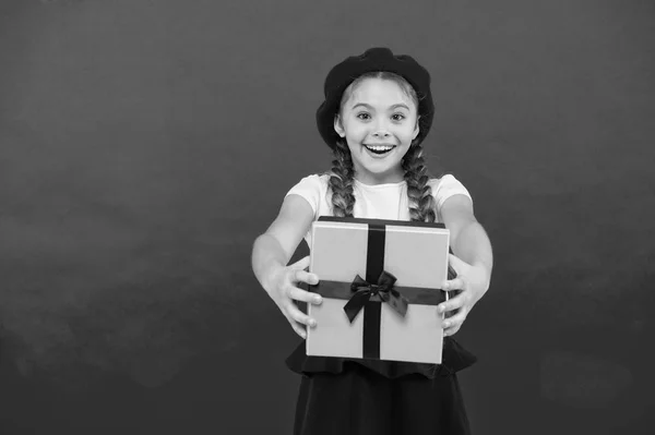 Ребенок взволнован распаковкой подарка. Маленькая симпатичная девочка получила подарочный пакет с ленточным бантом. Угадай, о чем мечтает твой ребенок. Лучшие игрушки и рождественские подарки. Малышка в беретной шляпе держит подарочную коробку. — стоковое фото