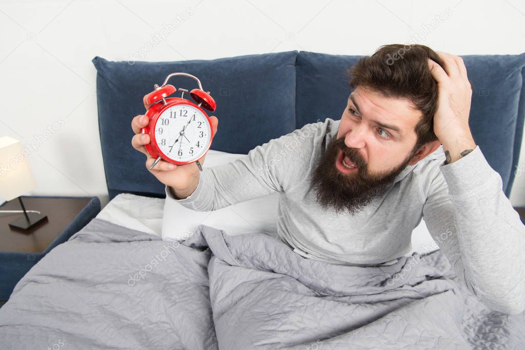 Get up with alarm clock. Overslept again. Tips for waking up early. Man bearded sleepy face bed with alarm clock in bed. What terrible noise. Turn off that ringing. Problem early morning awakening