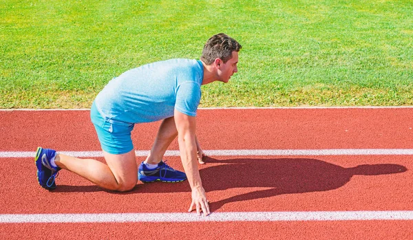 Man athlete runner stand low start position stadium path sunny day. Runner ready to go. Make effort for victory. Sport motivation concept. Adult runner prepare race at stadium. How to start running — Stock Photo, Image