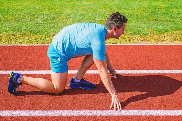 Make effort for victory. Runner ready to go. Adult runner prepare race at stadium. How to start running. Sport tips from professional runner. Man athlete runner stand low start position stadium path