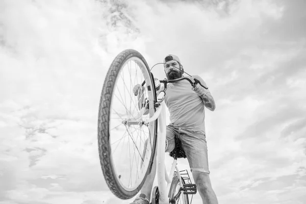 A kerékpáros teljesítmény optimalizálása. Férfi szakállas hipster lovagol kerékpár alsó nézet ég háttér. Modern kerékpáros kultúra. Kerékpárral leküzdeni az akadályokat. Hipster készen áll a trükkre. — Stock Fotó