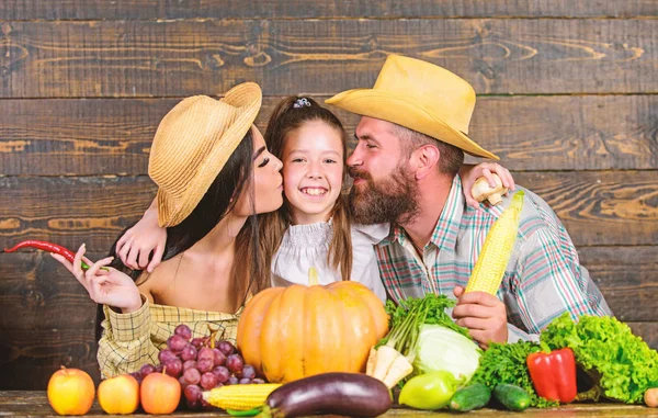 Family rustic style farmers at market with vegetables fruits and greenery. Parents and daughter harvest festival. Family farm concept. Family farmers with harvest wooden background. Grown with love