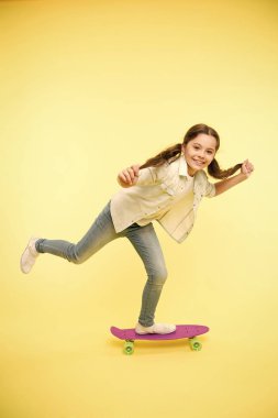 Kız penny Yönetim Kurulu sarı arka plan binmek. Çocuk penny Yönetim Kurulu ile eğleniyor. Kaygısız mutlu binmek. Çocukluk hobi favori aktivite. Genç nesil hobi. Çocuk güler yüz kaykay üzerinde durmak