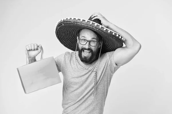 Koop souvenirs van reizen. Man dragen sombrero hoed winkelen gele achtergrond. Man met baard gelukkig in sombrero. Souvenir gift uit het buitenland. Man greep boodschappentas. Souvenir te kopen voor vrienden en familie — Stockfoto