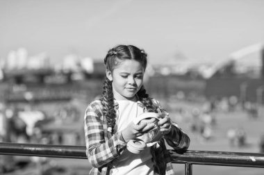 Küçük kız dışarıda yürürken katlanabilir kulaklık tutuyor. Modern müzik aleti. Katlanabilir kulaklıkların faydaları. Katlanabilirlik onu daha taşınabilir yapıyor. En iyi katlanabilir ve taşınabilir kulaklıklar.