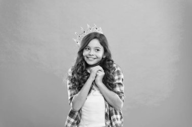 Tatlı kız mavi arka planda dururken taç takıyor. Prenses konsepti ol. Prenses olmayı hayal eden her kız. Küçük hanım prenses. Hayaller gerçek olur. Çocuk prensesin altın taç sembolünü takıyor.