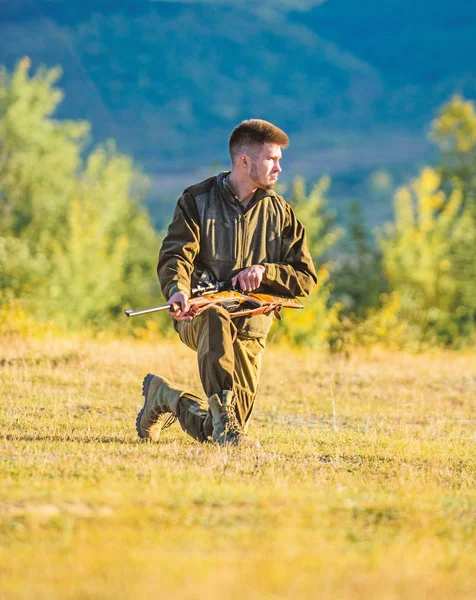 Hunting shooting trophy. Hunter with rifle looking for animal. Man charging hunting rifle. Hunting as male hobby and leisure. Hunter khaki clothes ready to hunt hold gun mountains background