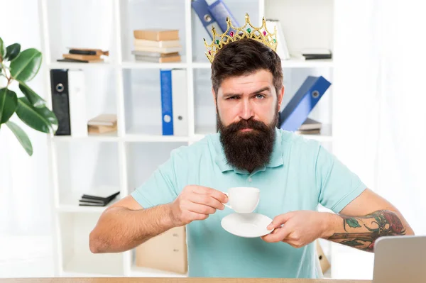 Man bearded manager businessman entrepreneur wear golden crown on head. Relaxed top manager drinking coffee. Confident boss enjoying his glory. King of office. Head of department. Head office concept
