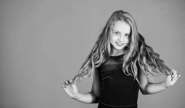 Ballroom latin dance hairstyles. Kid girl with long hair wear dress on violet background. Hairstyle for dancer. How to make tidy hairstyle for kid. Things you need know about ballroom dance hairstyle