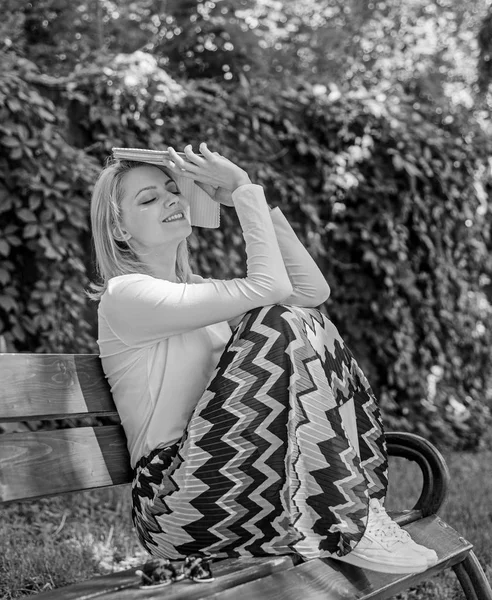 Träumen vom Happy End. Mädchen sitzen Bank entspannen mit Buch, grüne Natur Hintergrund. Dame hübsche Bücherwurm verträumt Buch lesen draußen sonnigen Tag. Frau liest verträumt Buch im Garten — Stockfoto