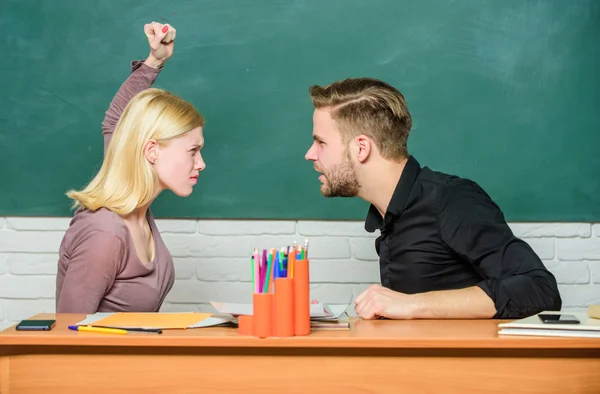Conflict situation. Teacher and schoolmaster are at quarrel. Angry woman going to man with her fists. Couple arguing in classroom. University or college students back to school. High school education