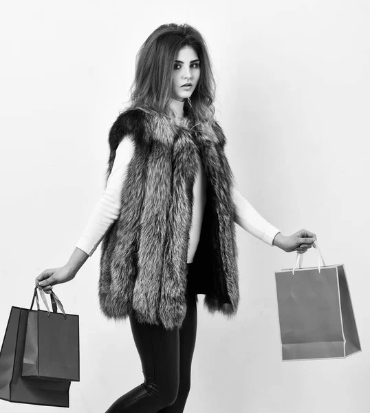 Fashionista buy clothes in shop. Girl makeup face wear fur vest white background. Woman shopping luxury boutique. Lady hold shopping bags. Shopping concept. Sales and discount on black friday — Stock Photo, Image