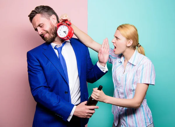 What time is it. Businessman with alcohol bottle and woman with alarm clock. Man suffering from alcoholism. Angry wife meeting drunk husband late at home. Addictive alcoholism or alcohol abuse