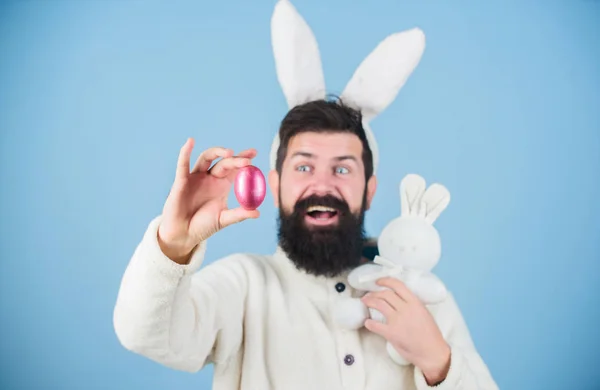 Decoração de ovos para a Páscoa. Homem barbudo com brinquedo de coelho e ovo de Páscoa. Hipster com longas orelhas de coelho segurando a lebre poedeira. Celebração de férias de primavera. Coelho da Páscoa entregando ovos coloridos — Fotografia de Stock