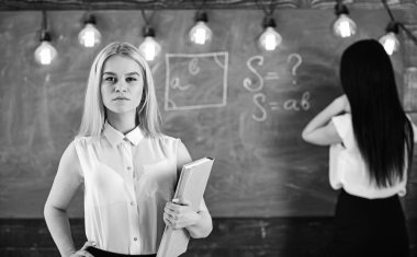 Öğrenci ve kursiyer kavramı. Kız defocused kara tahta arka plan üzerinde yazma Bayan ise kendinden emin görünüyor. Portre portre çekici genç kadın, öğrenci holding kitap sınıf