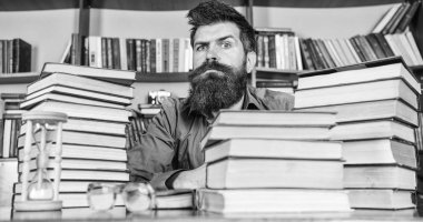 Katı yüz sit Kitaplığı'nda, eğitim sırasında kitaplar, kitap rafı arka plan üzerinde yığınları arasında adam. Öğretmen ya da öğrenci sakallı kum saati ve gözlük, defocused ile masaya otur. Kitap kurdu kavramı