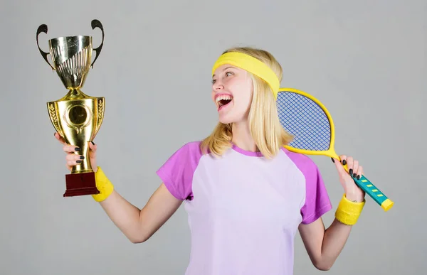 Atletik kız tenis raketi ve altın kadeh tutuyor. Tenis maçı kazan. Kadınlar spor kıyafetler giyer. Tenisçi şampiyonluğu kazandı. Birincilik. Spor başarısı. Zaferi kutlayın. Tenis şampiyonu — Stok fotoğraf